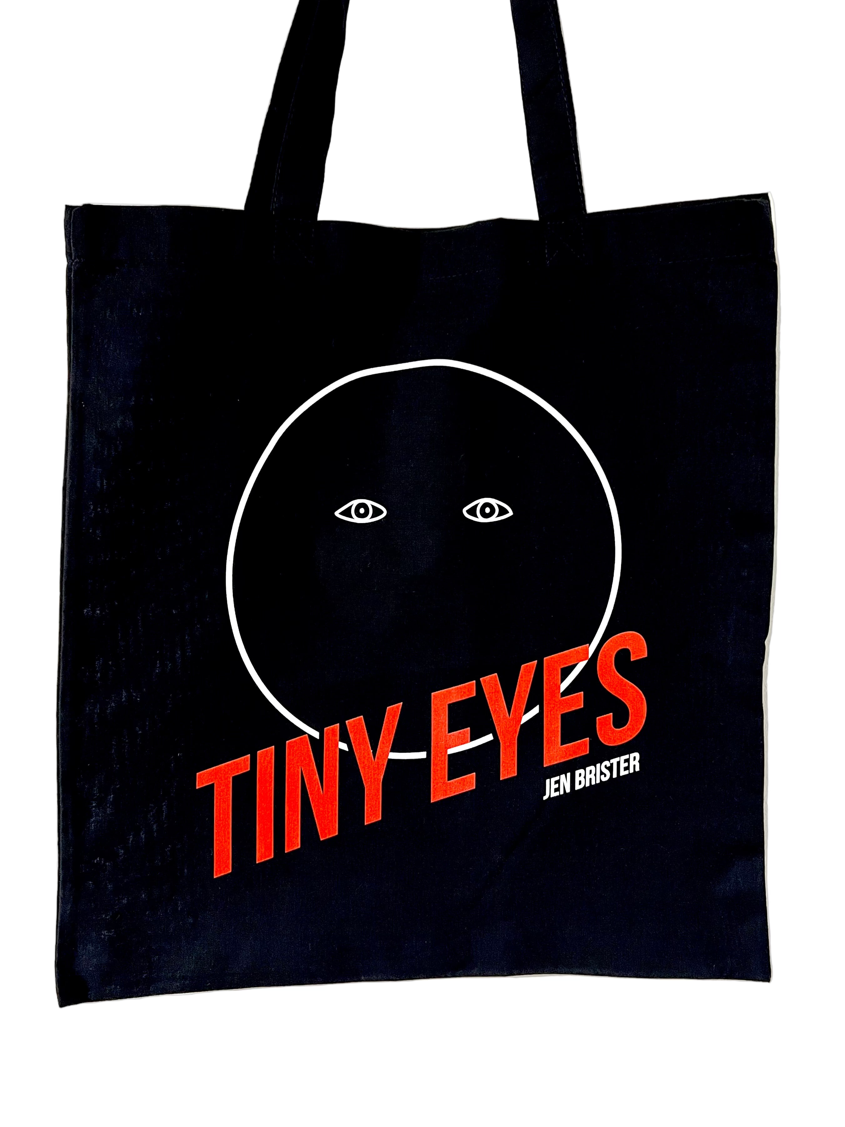 Black tote bag with 'Tiny Eyes' design and orange text